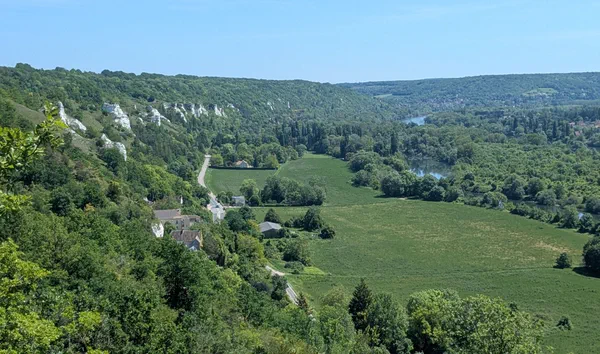 Vue panoramique d'une vall&eacute;e verdoyante avec des falaises calcaires sur la gauche, une rivi&egrave;re sinueuse et des arbres denses. V&eacute;theuil - Val-d'Oise. France