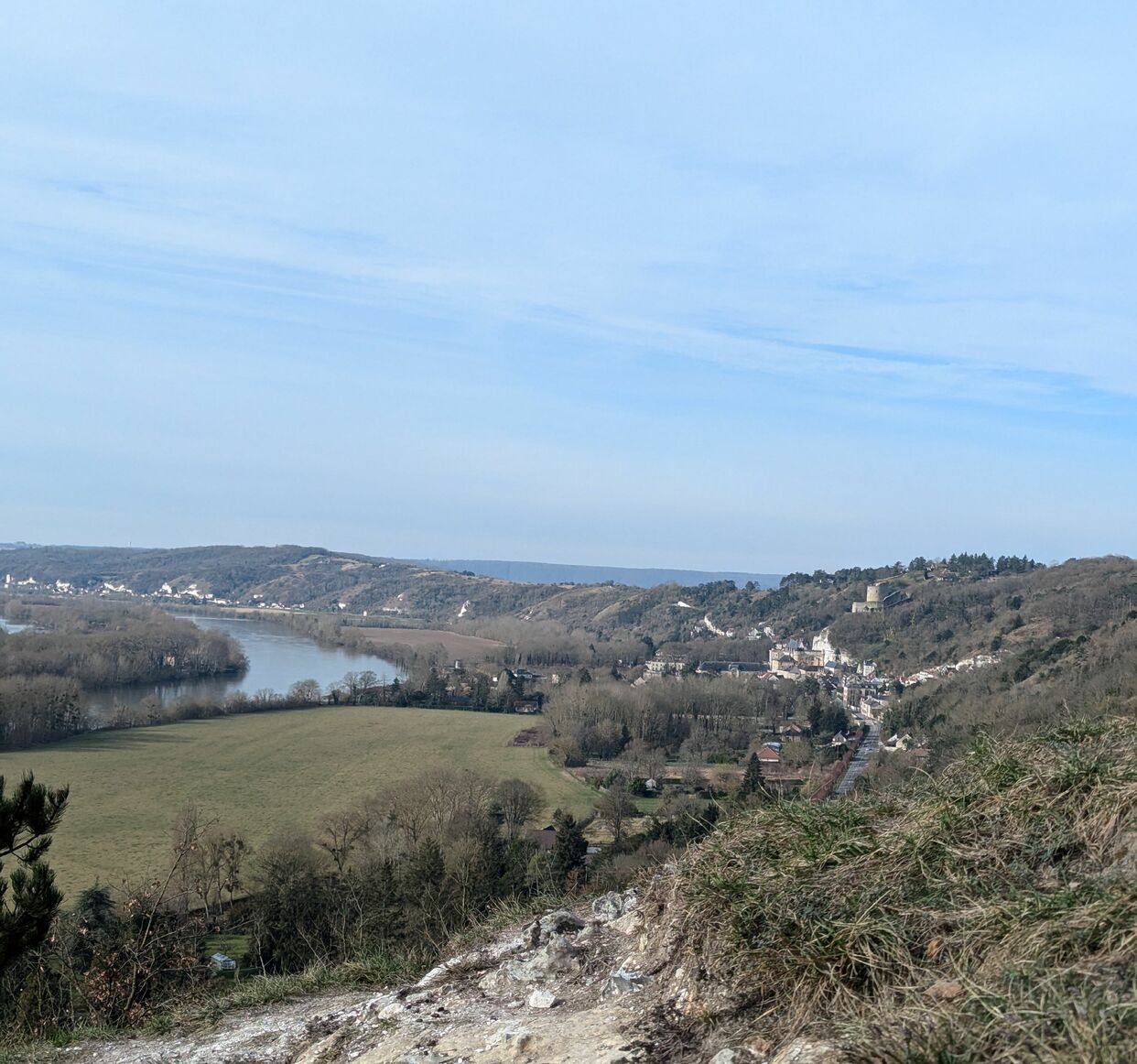 Vue panoramique d'une vall&eacute;e avec une rivi&egrave;re sinueuse, des collines bois&eacute;es et un village pittoresque, sous un ciel bleu clair avec quelques nuages &eacute;pars. V&eacute;theuil - Val-d'Oise. France