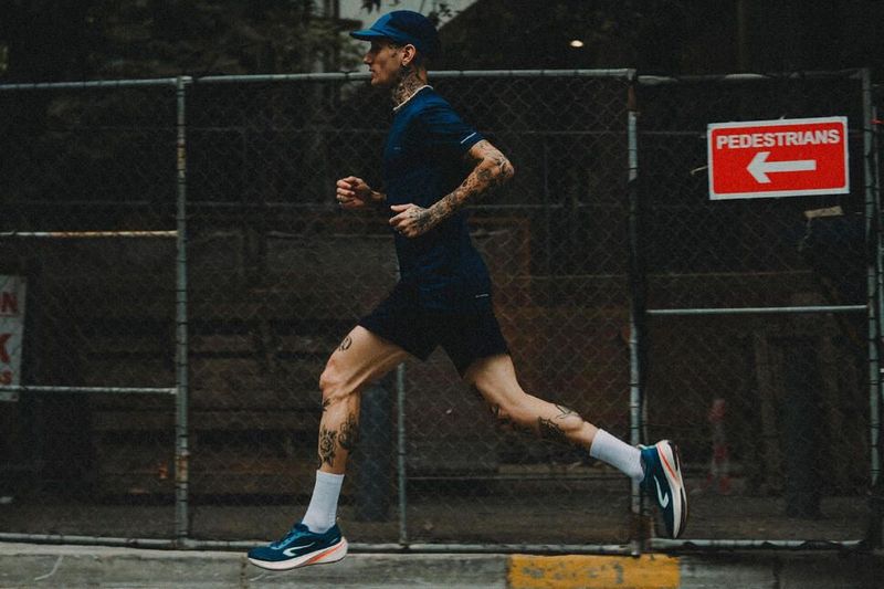 Temps marathon : homme de profil courant dans la rue avec panneau rouge "piétons" en anglais